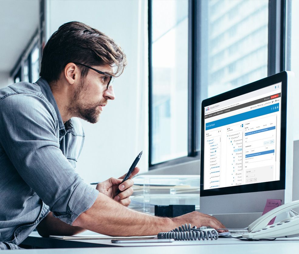 Businessman wearing glasses examines data on a computer screen in his office