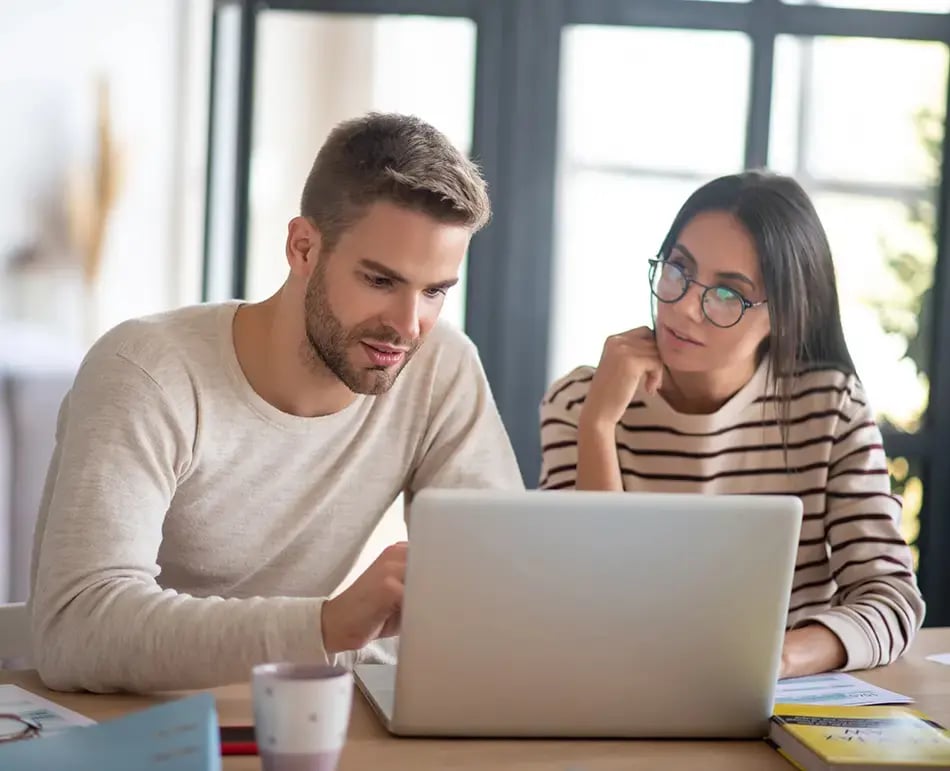 Happy buisiness couple looking at Bullhorn integration on their laptop