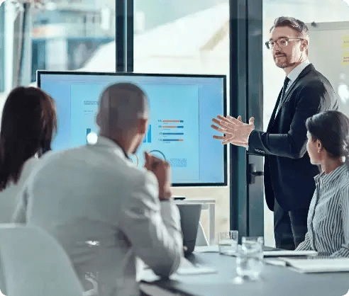 Man teaching managed IT services to his co-workers on a large computer monitor