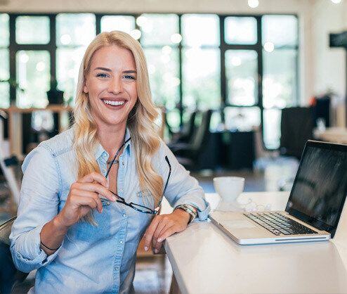 Femme regardant la caméra avec un ordinateur portable