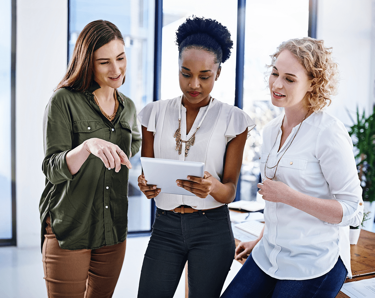 Three businesswomen work together on a tablet