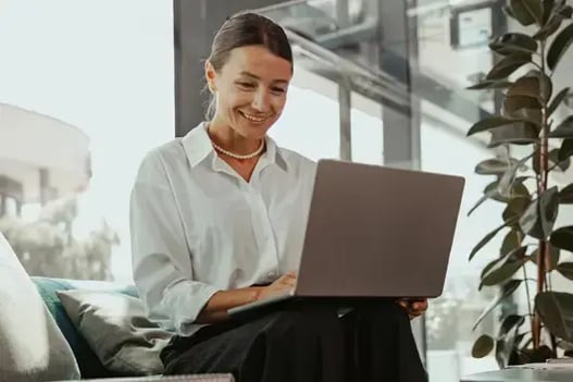 Femme souriante sur son ordinateur portable au bureau, ravie de voir Bullhorn intégré à Sage Intacct