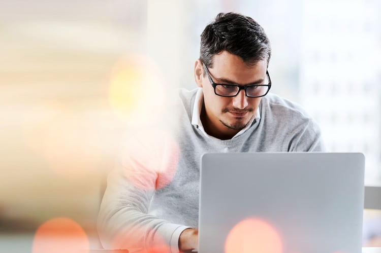 Businessman in glasses works at a laptop