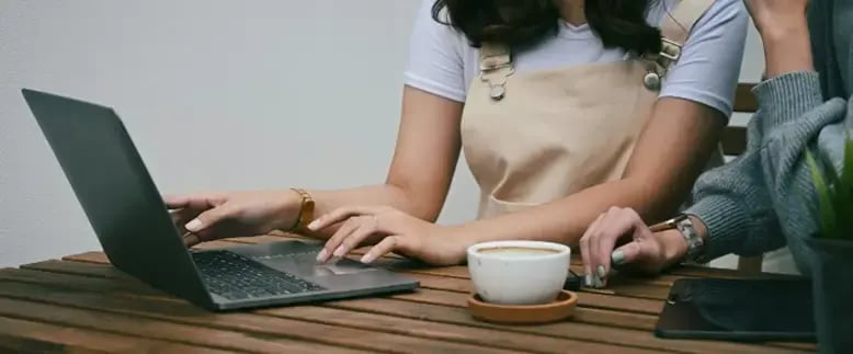 Two businesspeople use iDocuments on a laptop to automate purchasing, expenses, and sales order transactions
