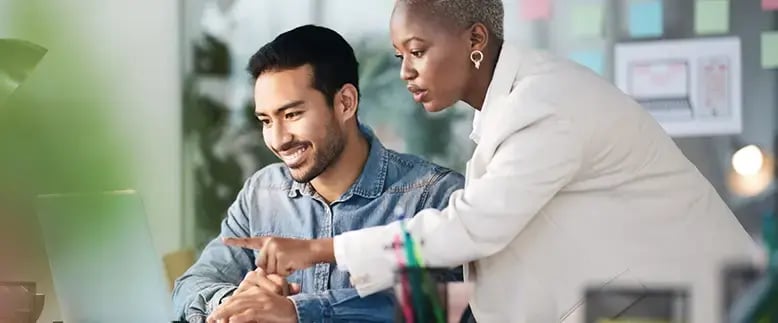 Smiling businessman and businesswoman examine data on a computer together